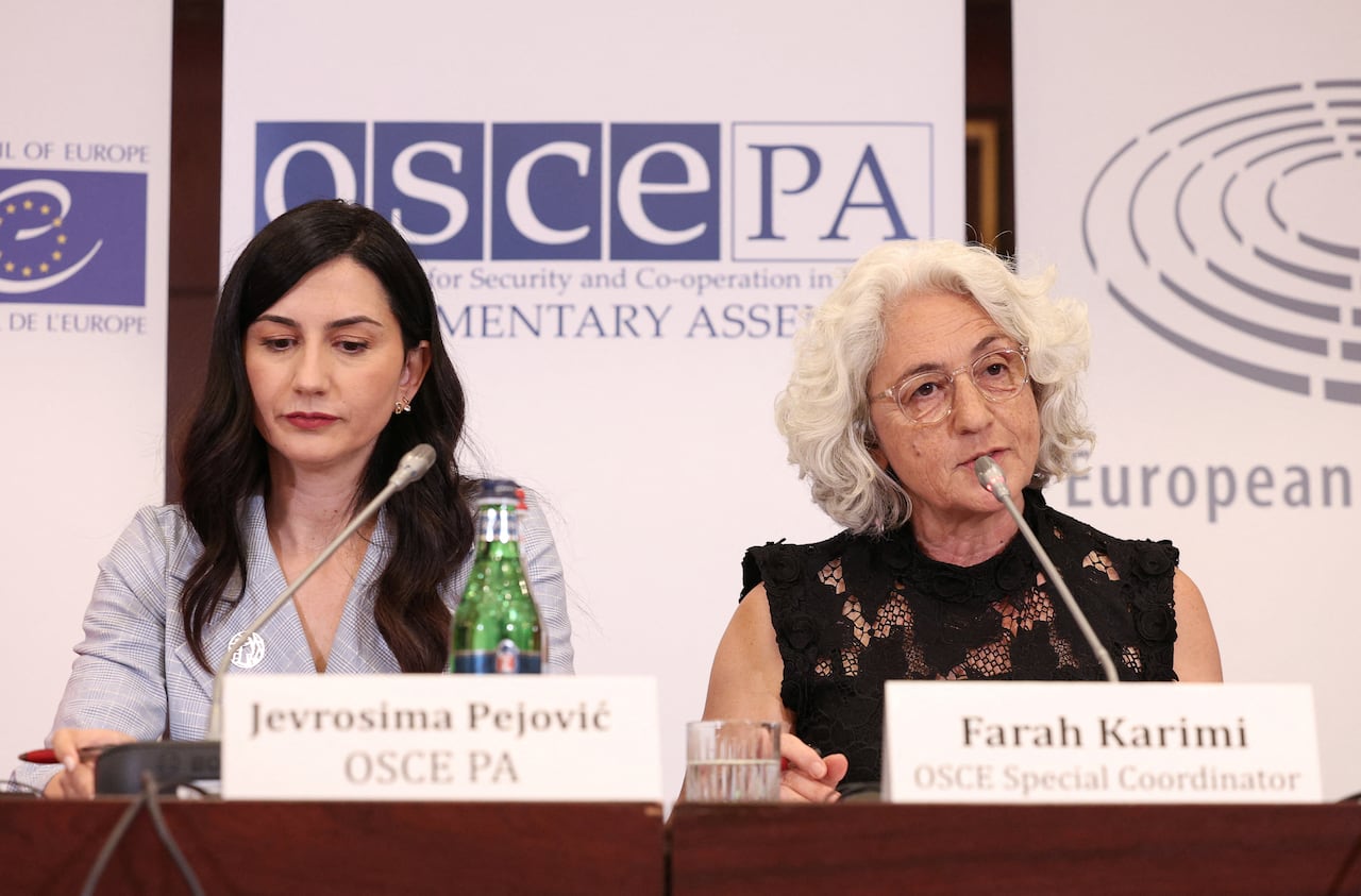 Two women on a panel speak into microphones