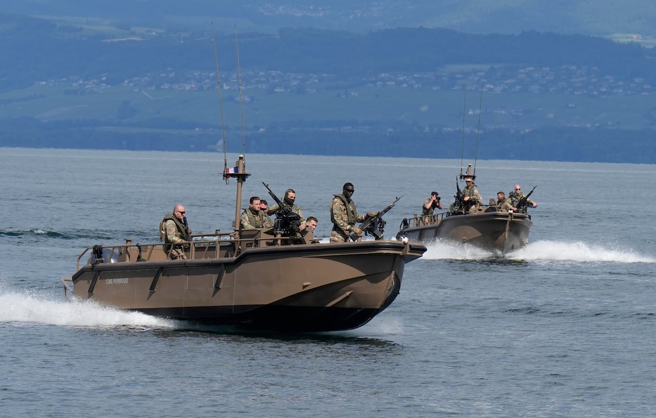 Armed police are seen on boats at sea.