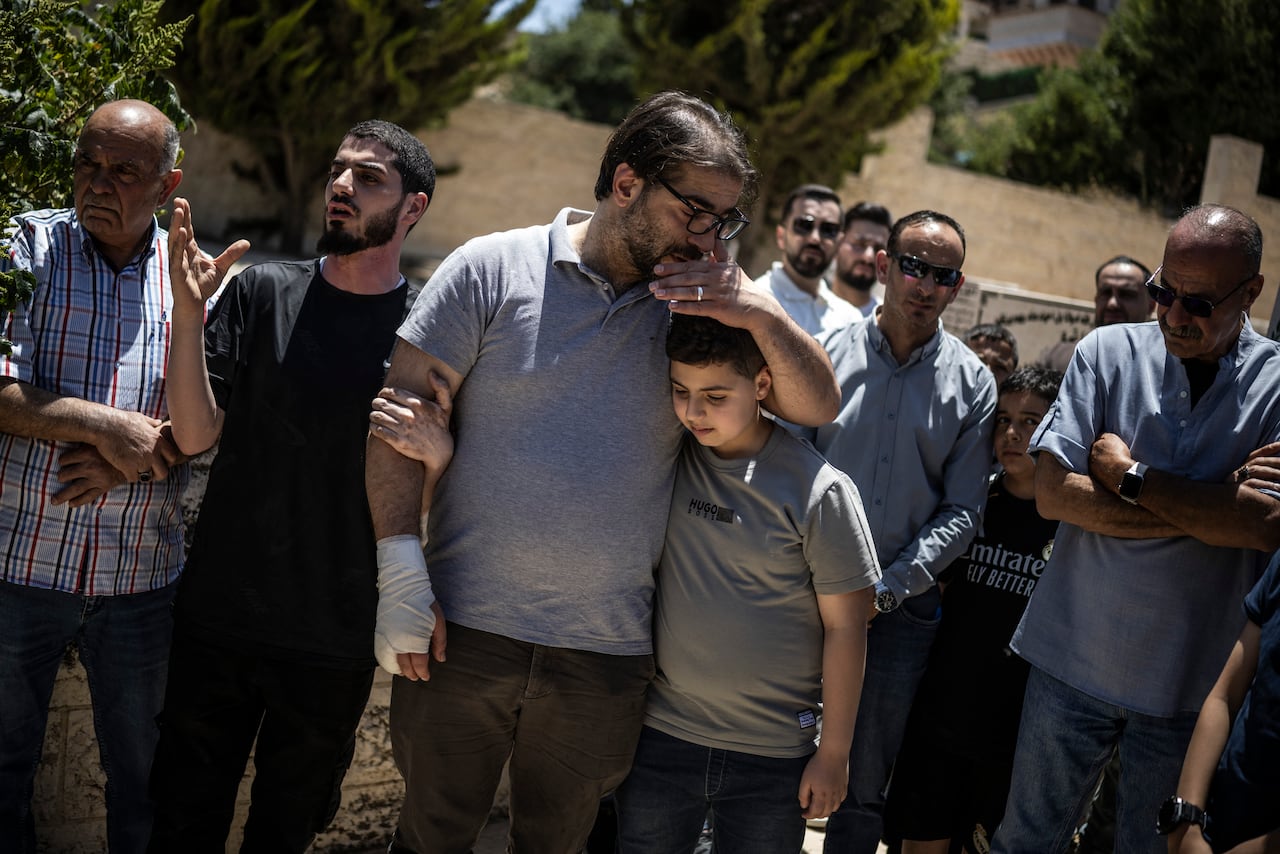 People embrace during a funeral service.
