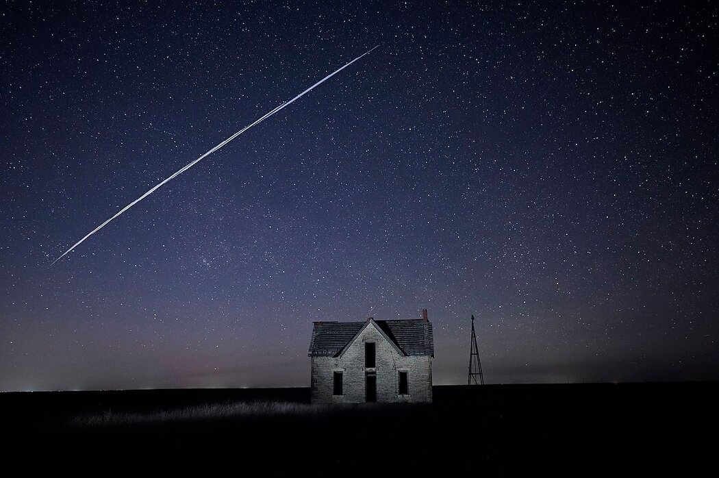 这张2021年拍摄的长时间曝光照片记录了SpaceX的一个星链卫星穿过堪萨斯州佛罗伦萨附近一栋古老石屋上空的景致。