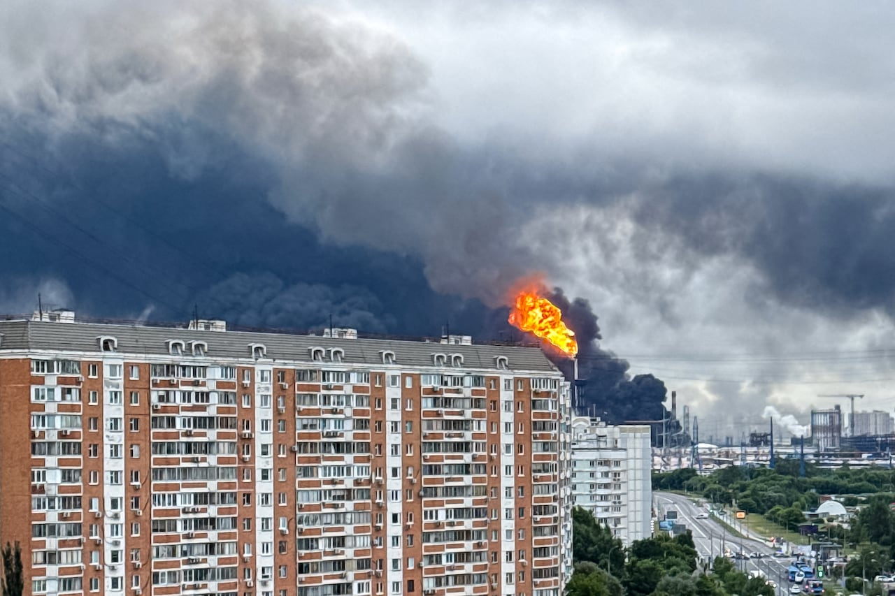 An aerial view shows a city with high-rise buildings and roads. An orange ball fire and large black clouds of smoke are shown in part of the scene.