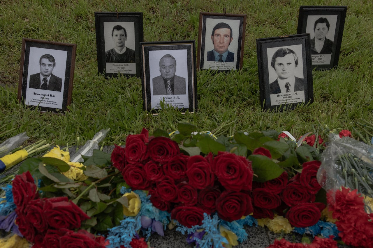 Framed photos are seen at a memorial surrounded by flowers.