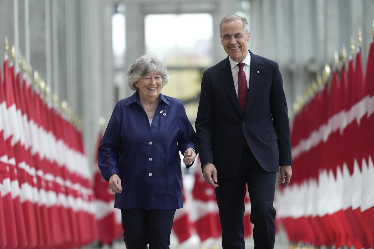 Two people walk between two rows of Canadian flags.