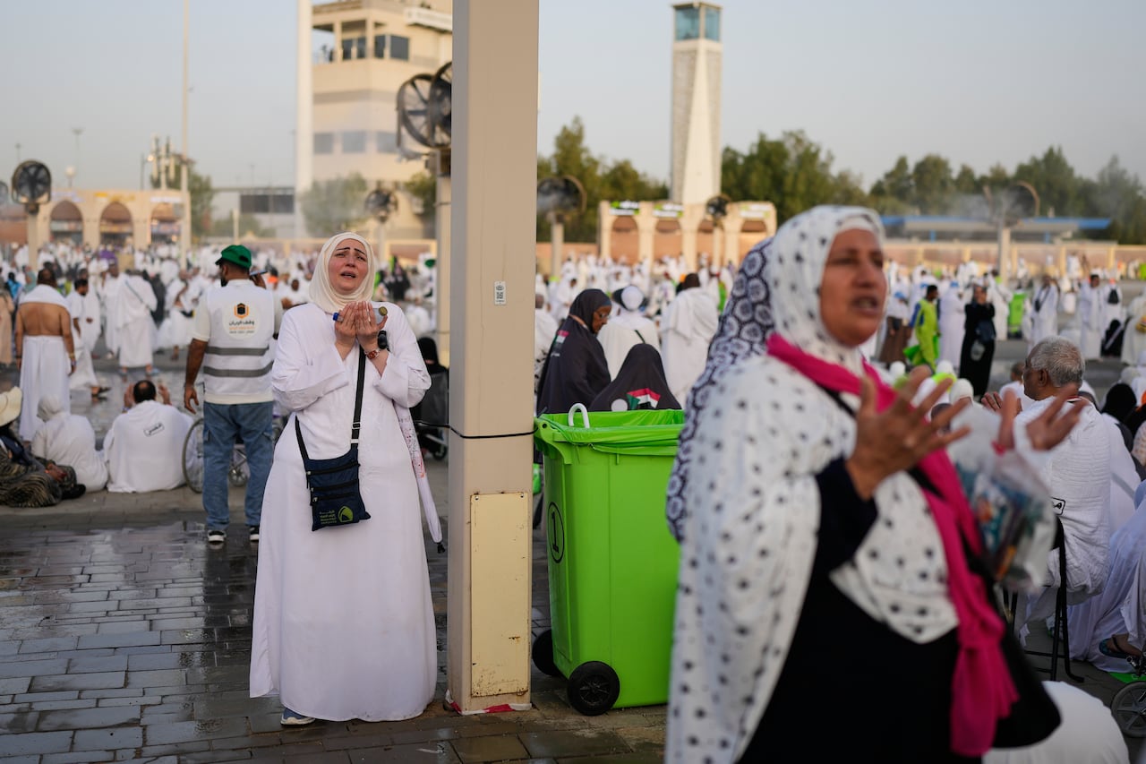 People in white stand in a square and pray