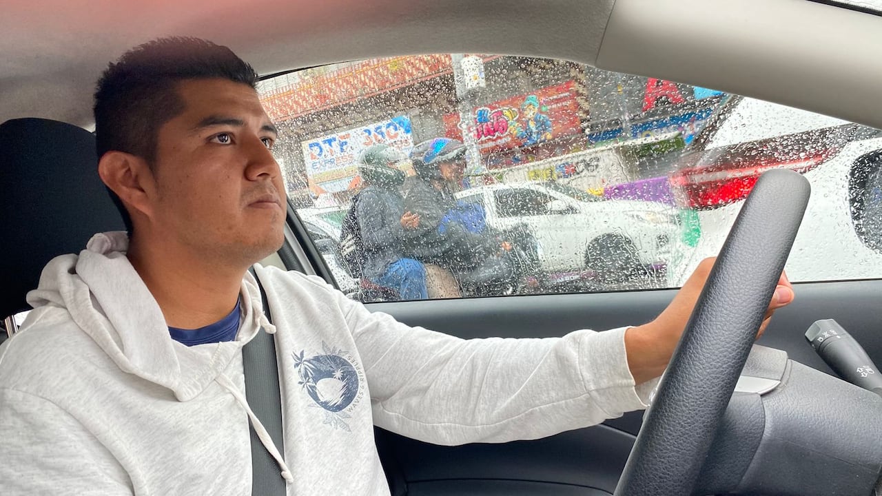 A young man in a sweatshirt at the wheel of a car.