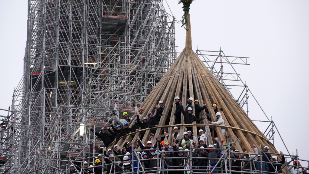 Workers celebrate the end of the reconstruction of the cathedral framework with a the traditional bouquet of flowers, at Notre de Paris cathedral, Friday, Jan. 12, 2024 in Paris. Workers mark a milestone in rebuilding the roof of fire-ravaged Notre Dame Cathedral in Paris ahead of December reopening. (AP Photo/Christophe Ena)