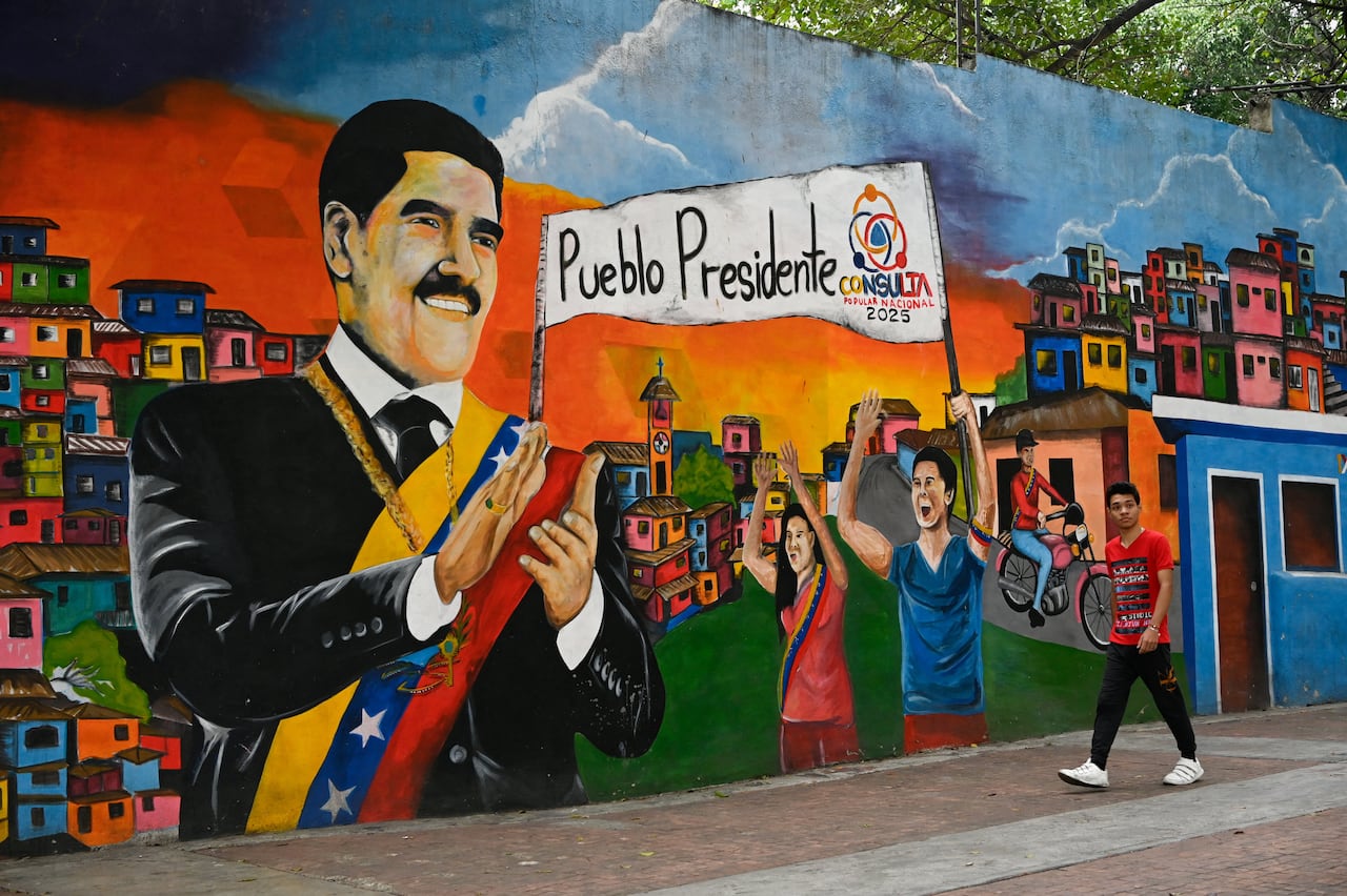 A man walking past a mural depicting Venezuela's ousted president Nicolás Maduro