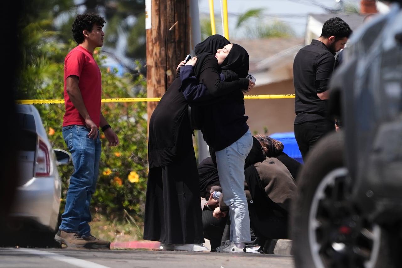 People embrace near an area cordoned off by police tape.