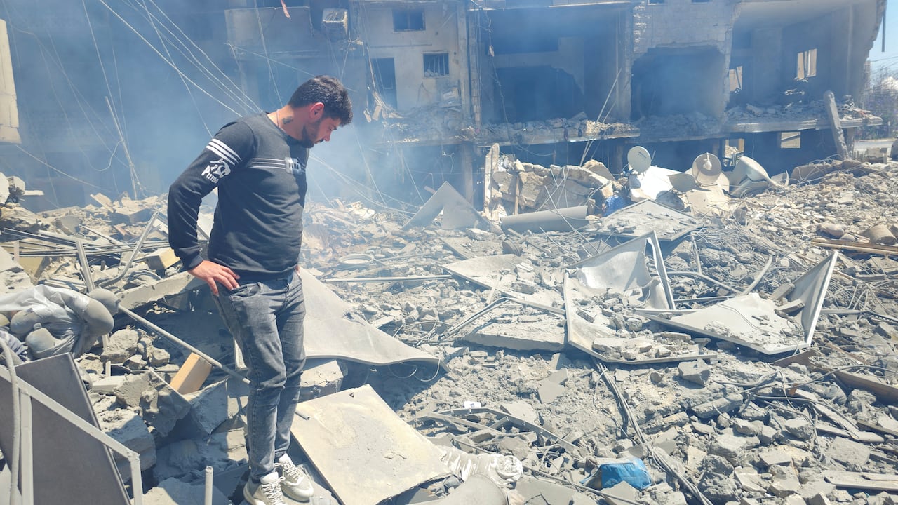 A man stands on top of rubble as he looks down at the pile of rubble.
