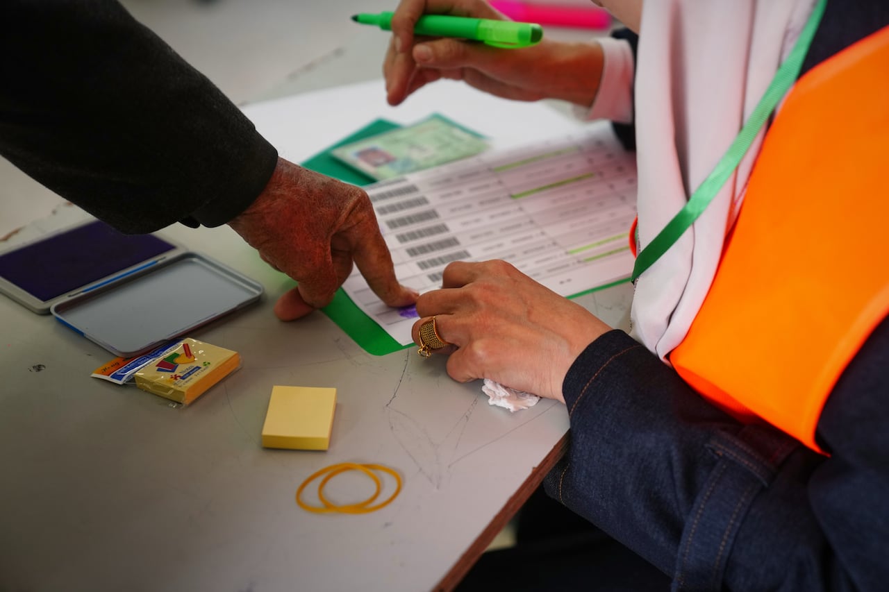 A voter stamps their thumb print on a ballot.