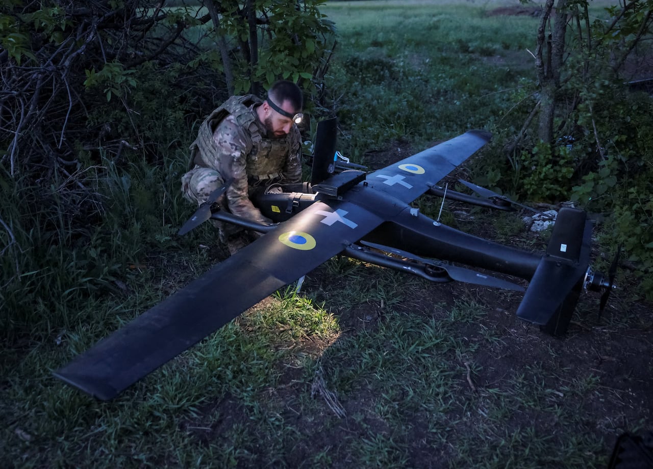 A Ukrainian serviceman stands over a large drone and prepares it to be launched towards Russian targets.