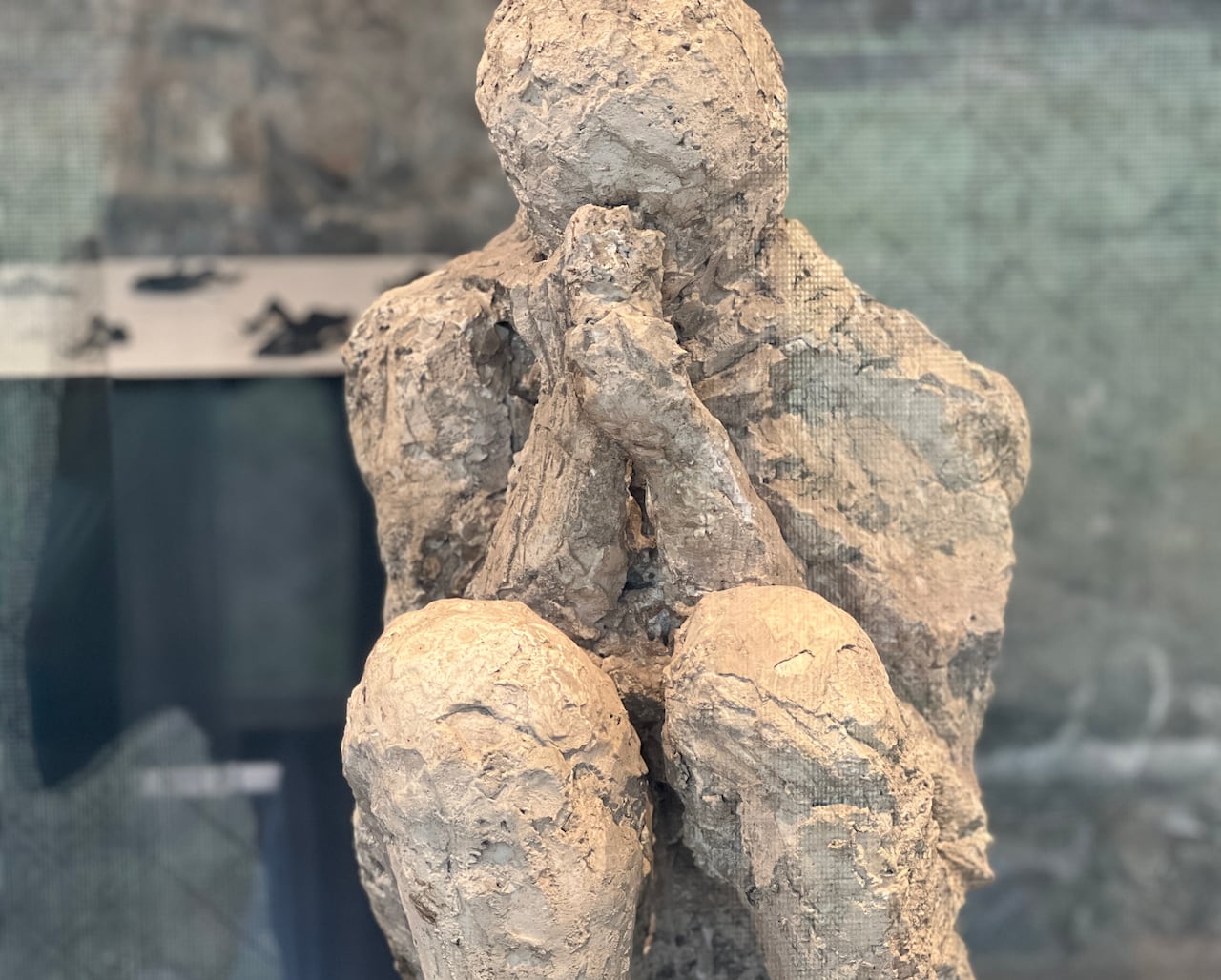 A cast figure of a sitting man holding his hands to his head.
