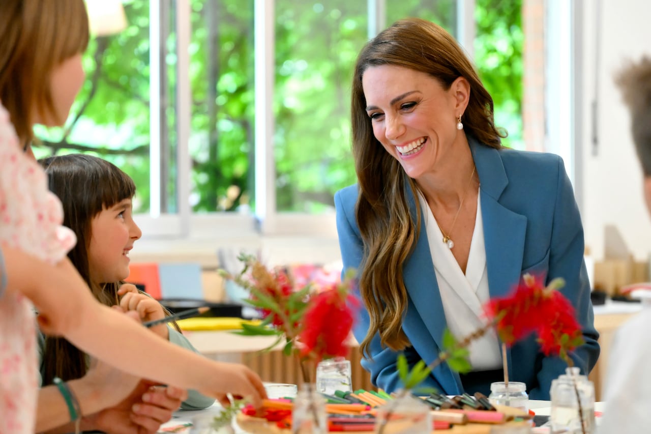 An adult smiles at children sitting at a table with them.