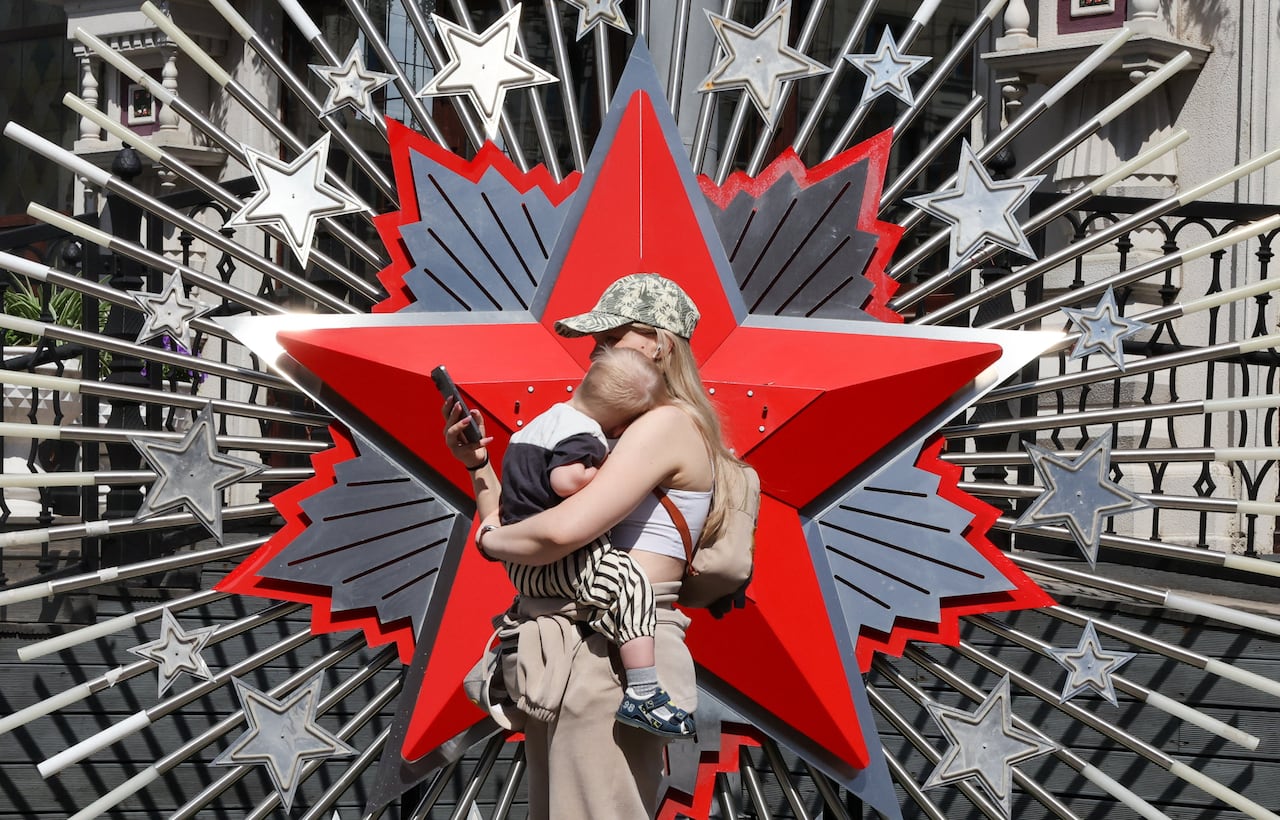A woman holding a child, near an installation in Moscow, ahead of Victory Day celebrations