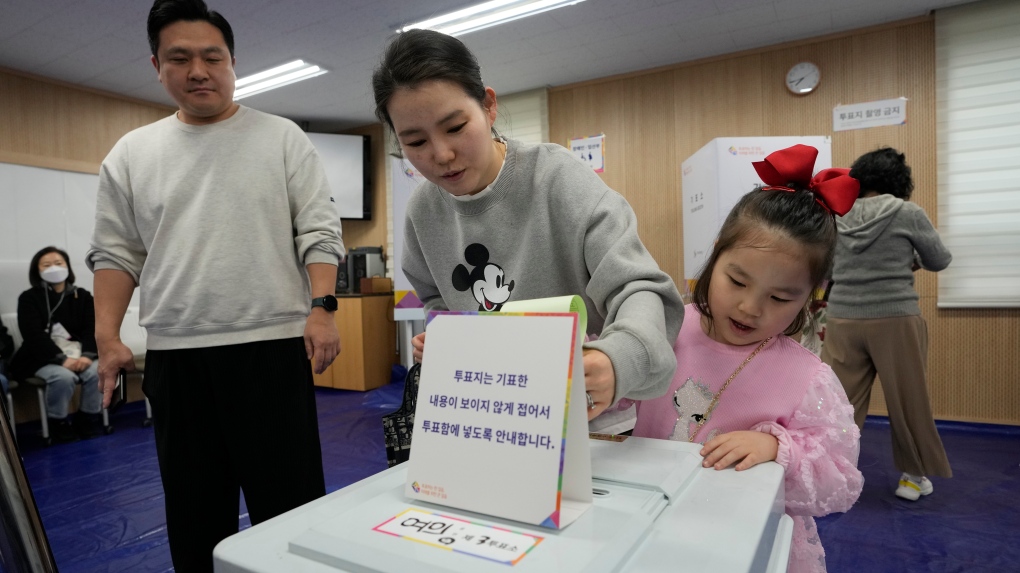 A mother casts her vote with her daughter for the parliamentary election at a polling station in Seoul, South Korea, Wednesday, April 10, 2024. (AP Photo/Ahn Young-joon) 