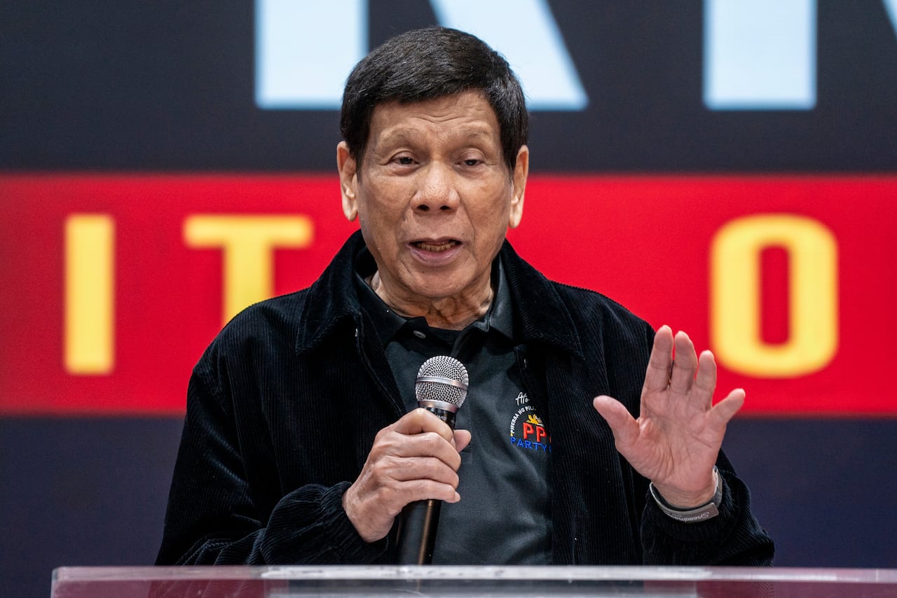 Former Philippines president Rodrigo Duterte holds a mic while speaking, his other hand raised emphatically