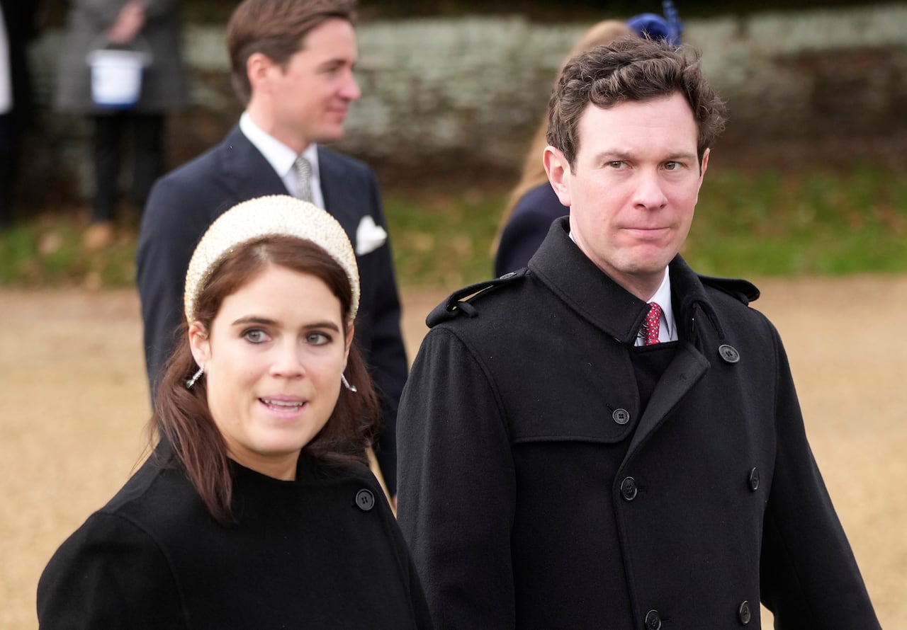 Two people walk along a gravel path, with two people behind them.