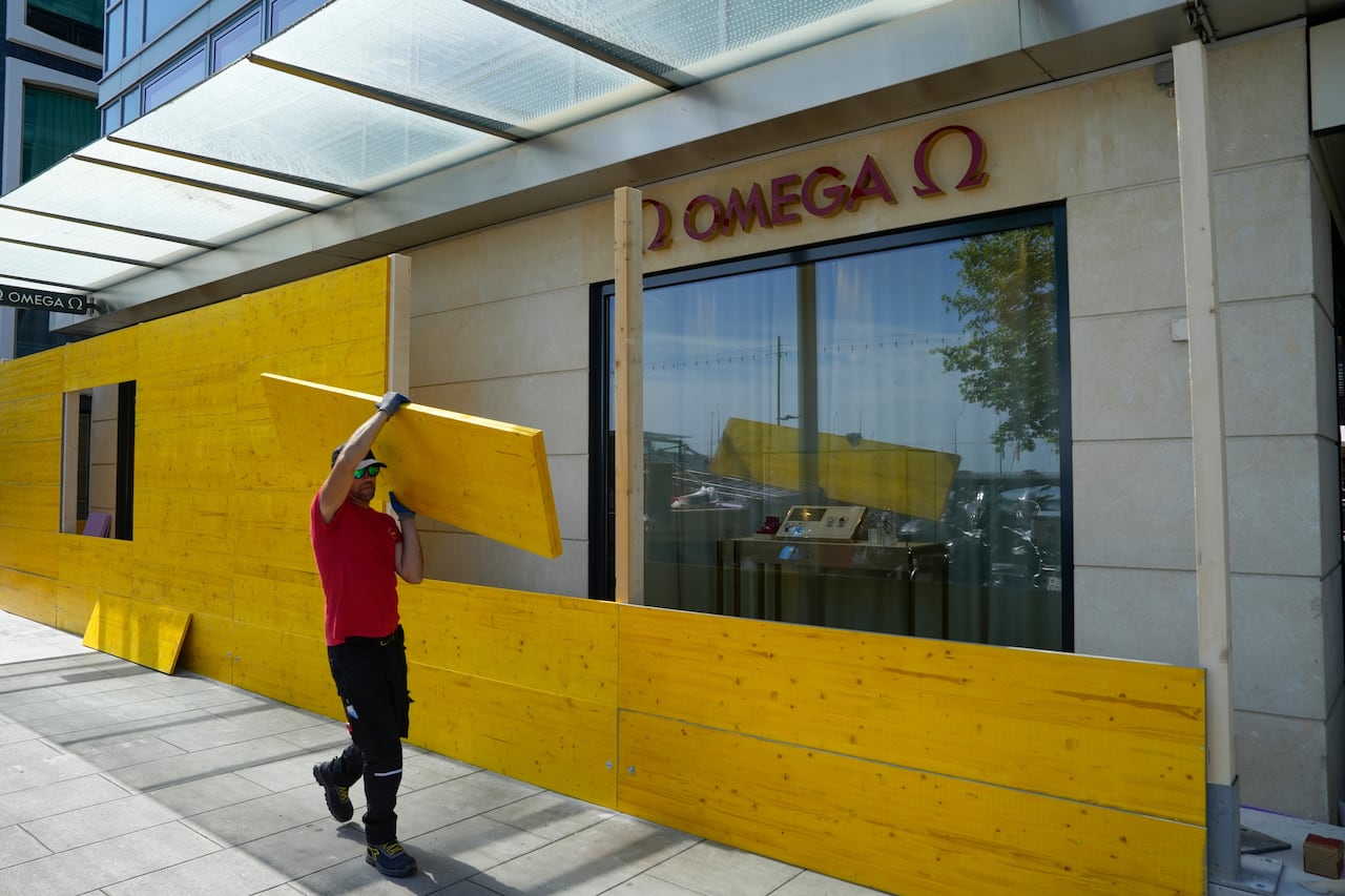 Workers install wood panels in front of a luxury store.