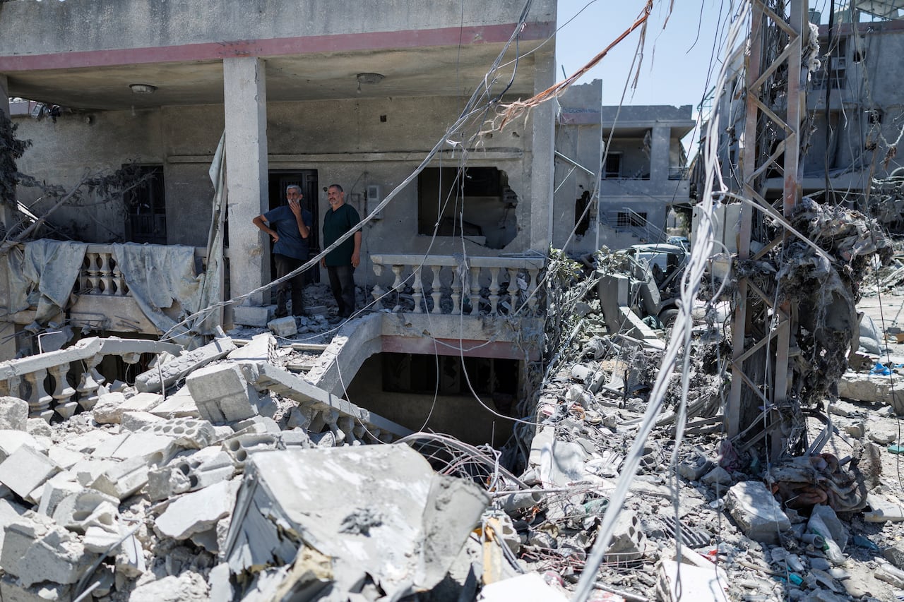 2 people stand amid the rubble of a collapsed building
