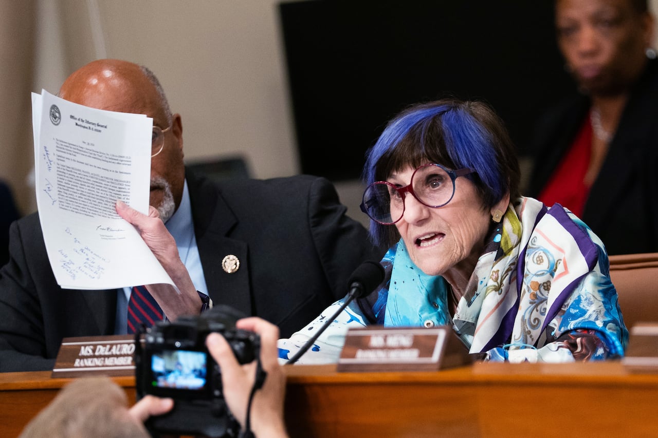A person holds up pieces of paper while speaking.