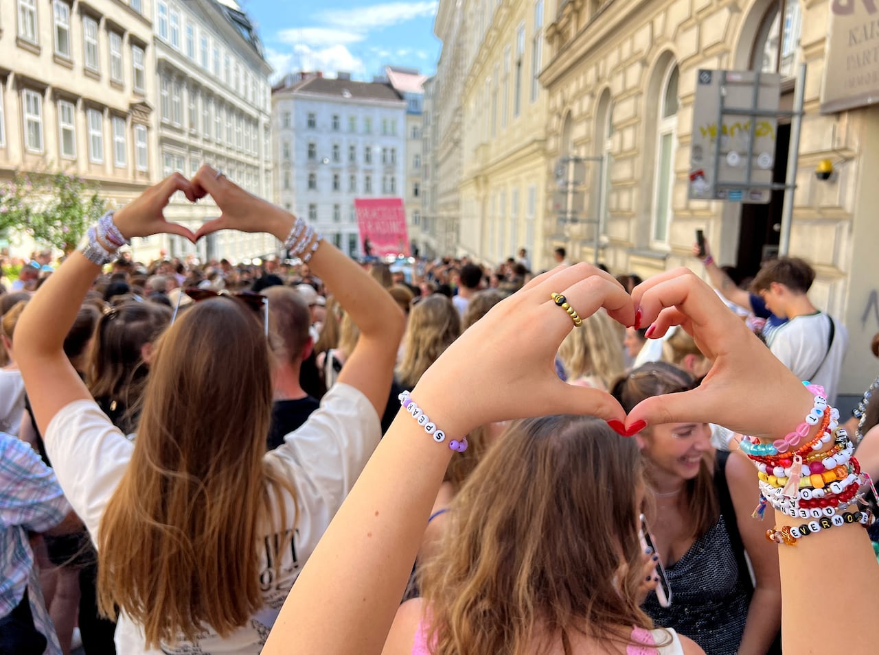 Crowds of young people, some wearing homemade bracelets, gather in a European street.