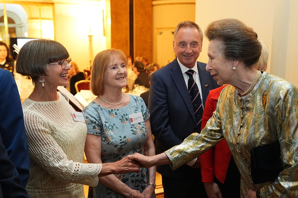 Two people shake hands while three other people look on.