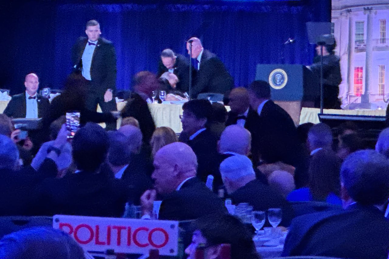 Security personnel gather around a person during a formal dinner.