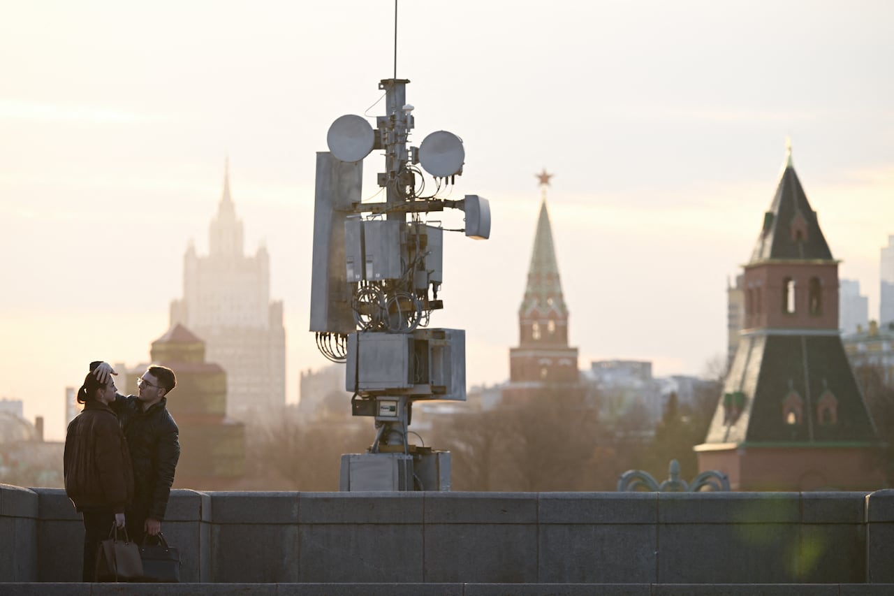 TOPSHOT - A couple interacts on the Moskvoretsky bridge in front of a cell tower in central Moscow on March 17, 2026. (Photo by Igor IVANKO / AFP via Getty Images)