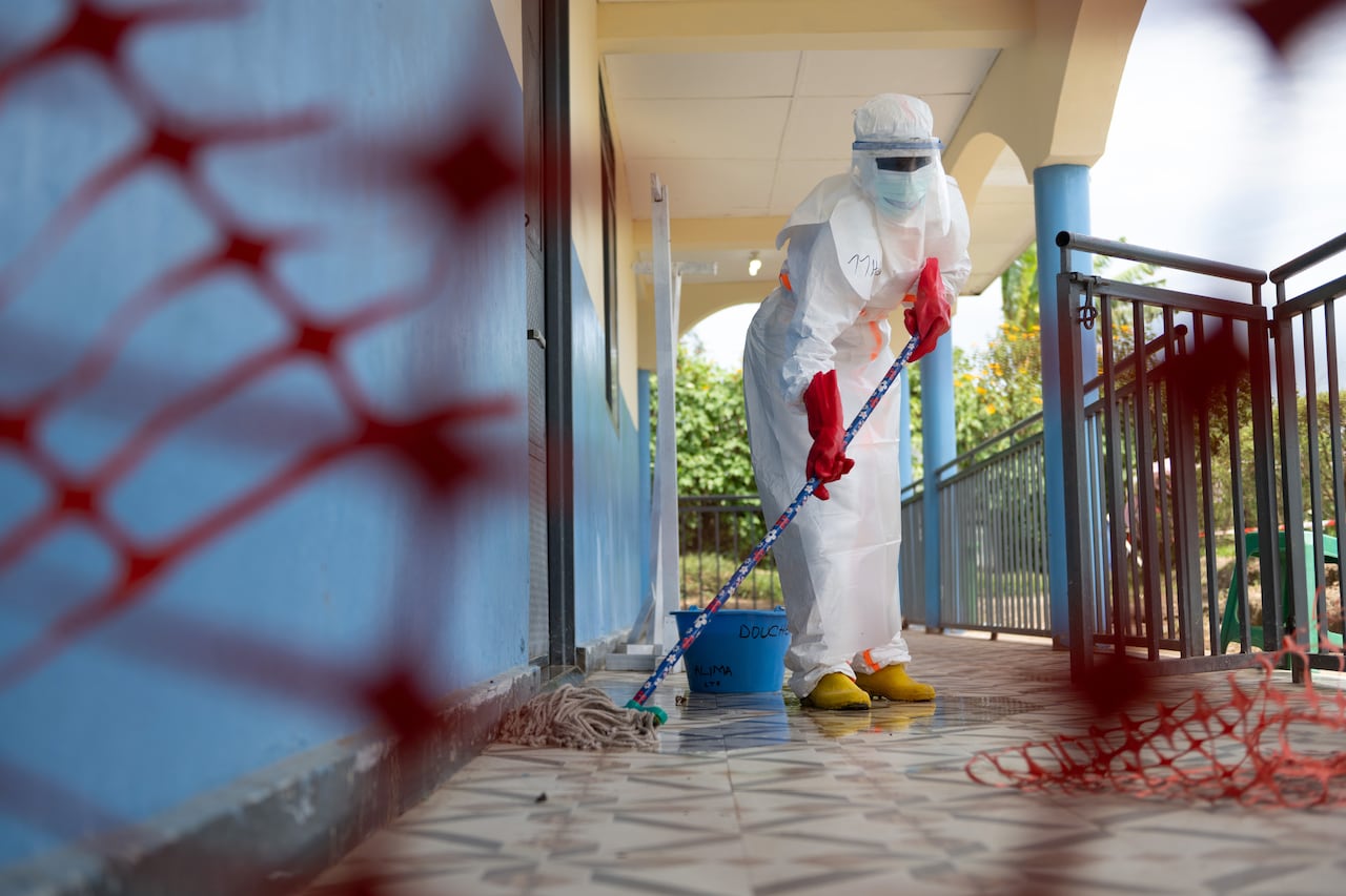 A health-care worker in a hazmat suit mops the floor.