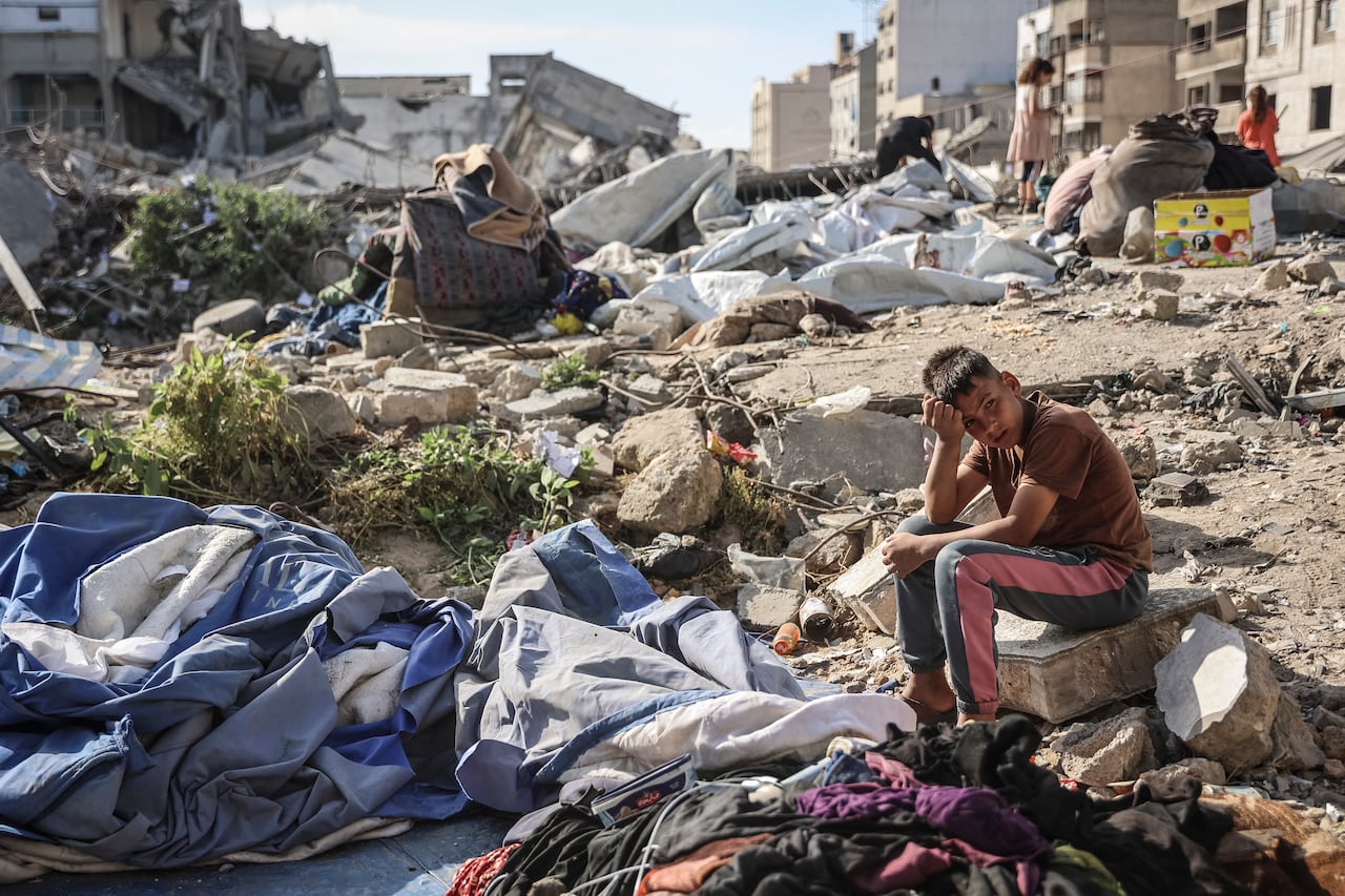 A boy sitting at a site in Gaza City, where an Israeli military strike previously hit.