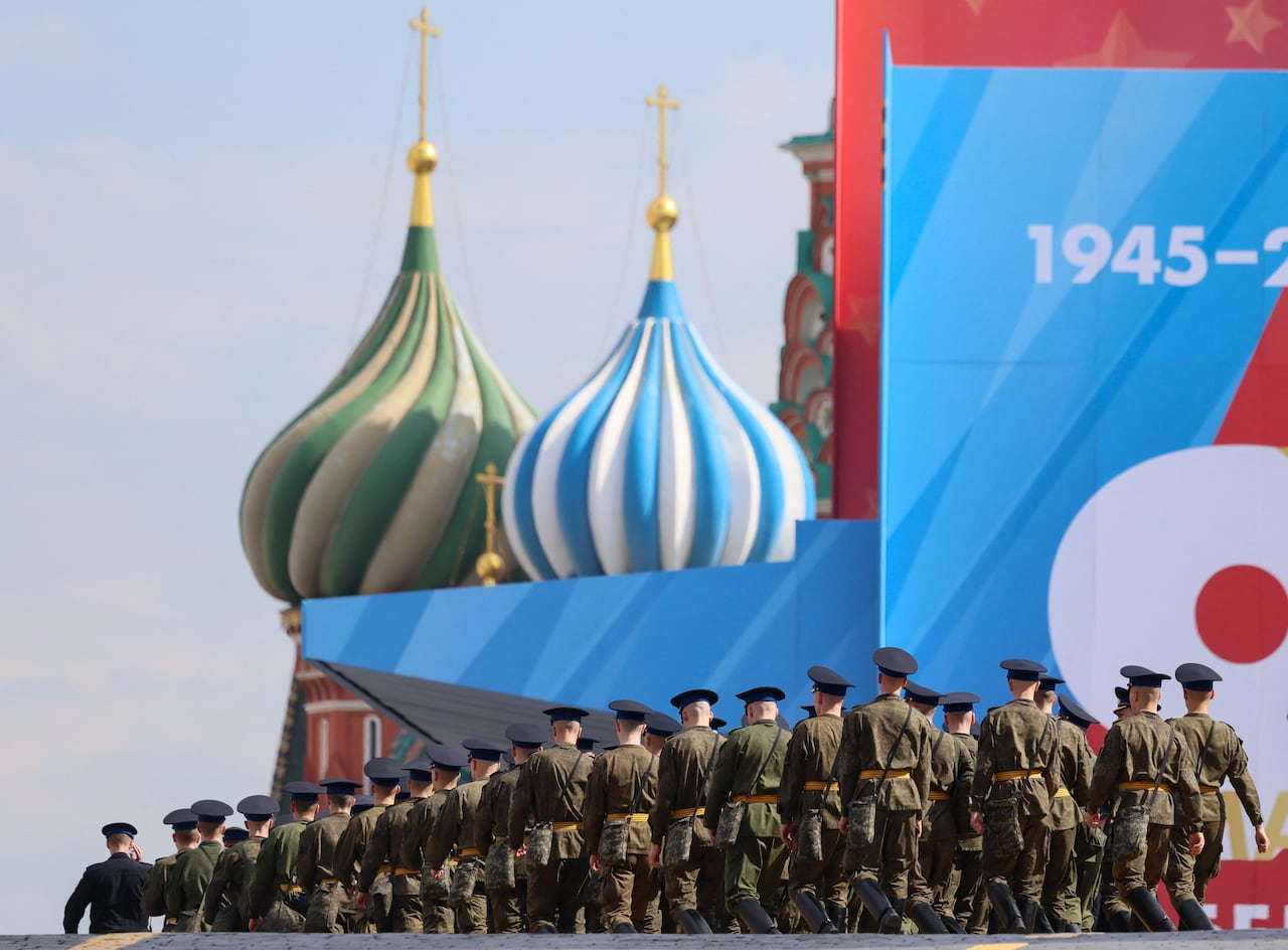 Soldiers march toward a building with elaborate domes on its roof.