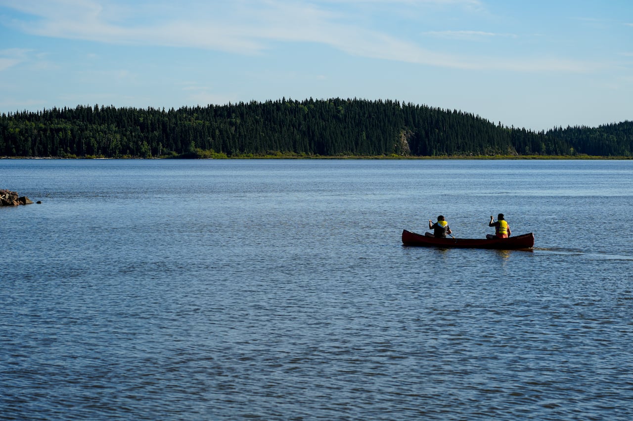 Two men take a canoe out onto a lake.