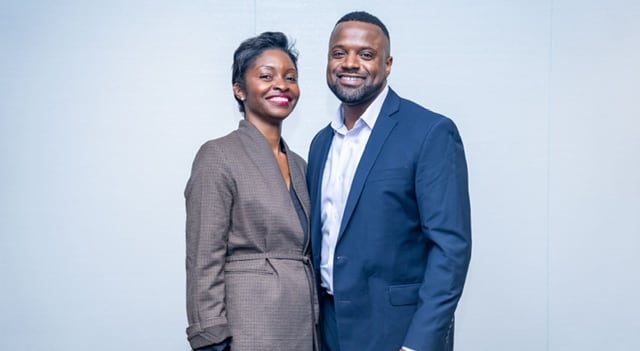 A woman and a man stand together, smiling at the camera