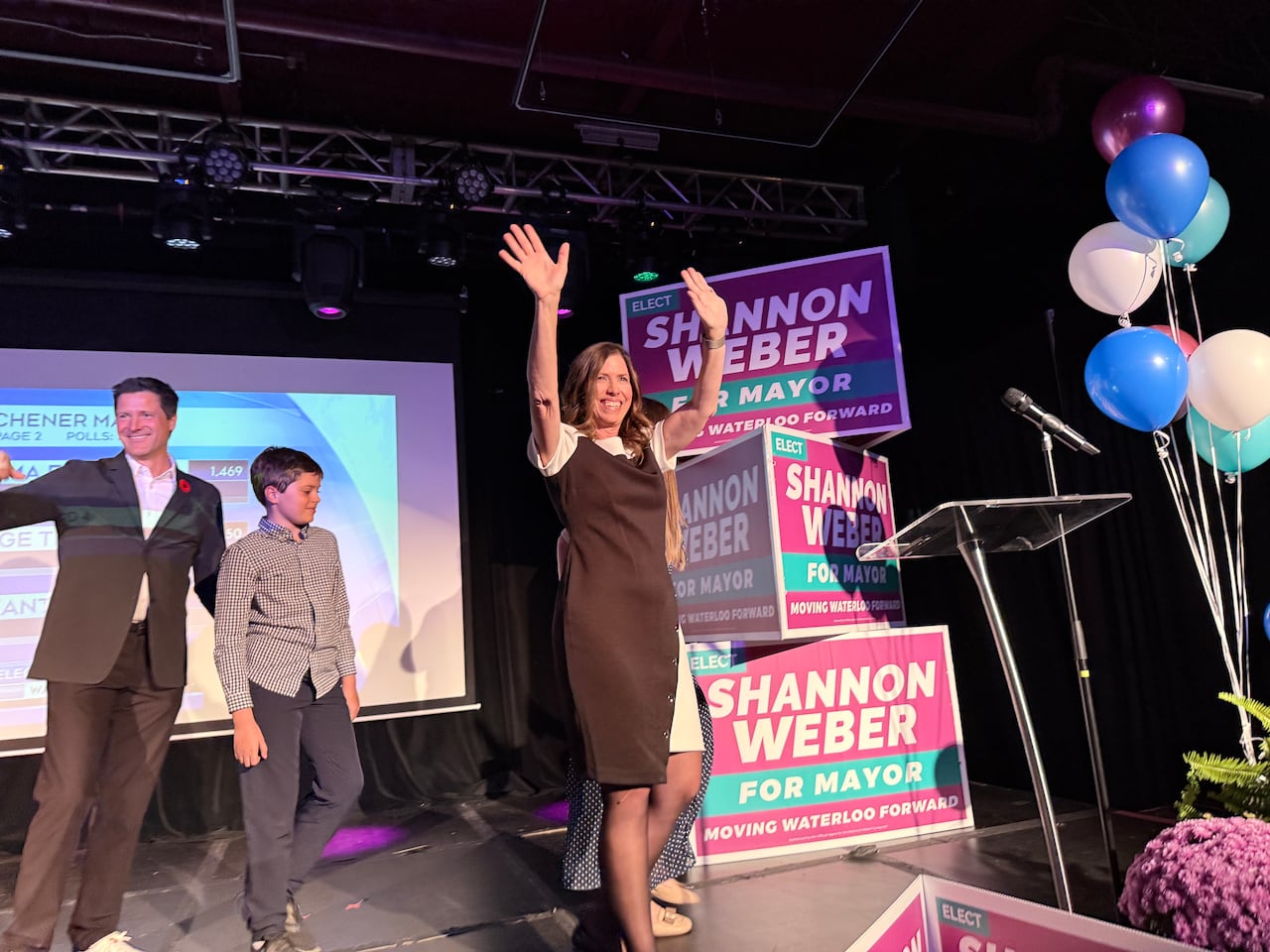 A woman waves on stage.