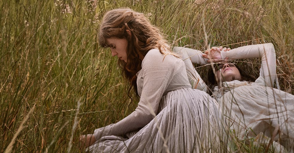 Two women side by side in a field.