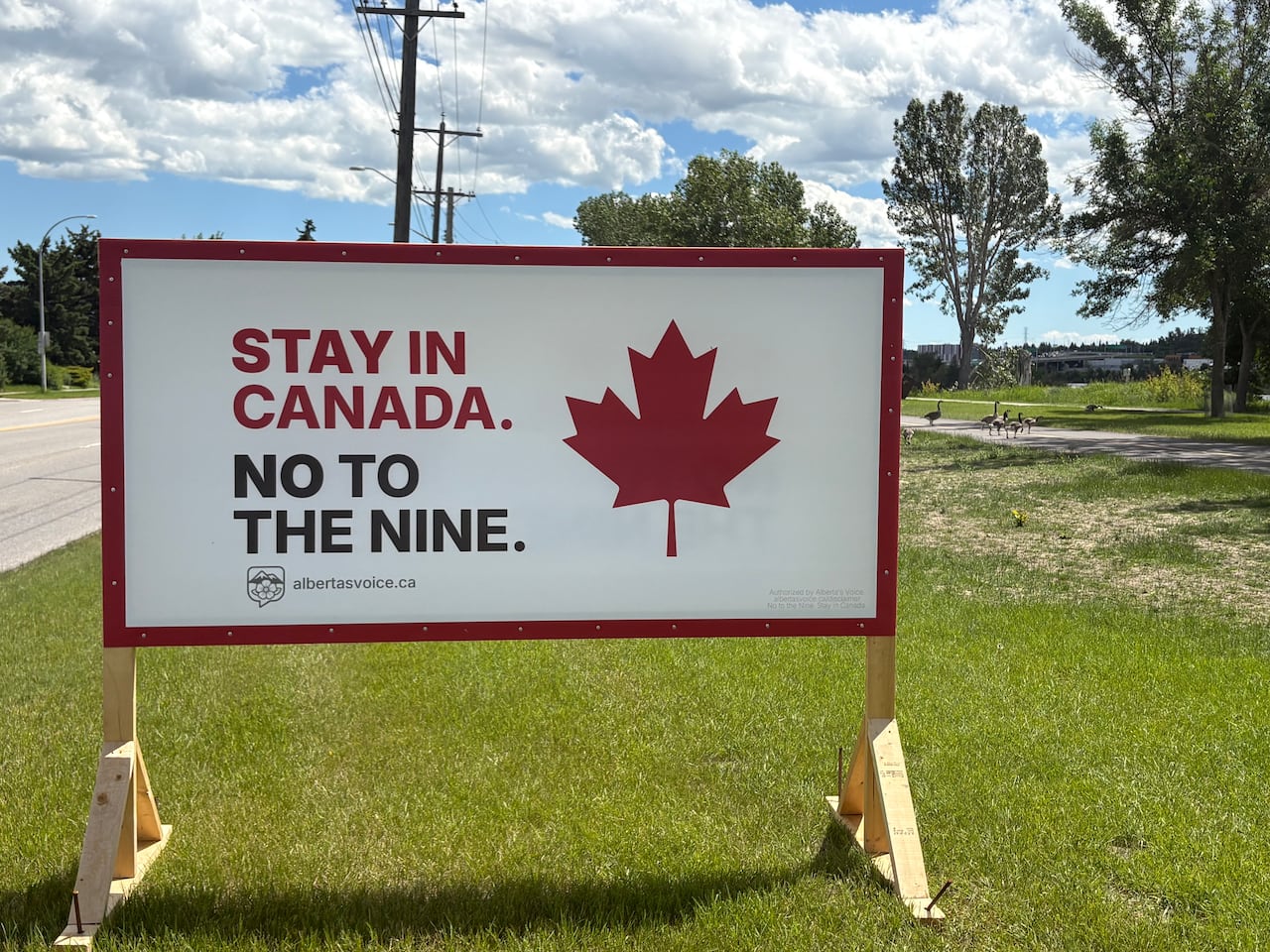 A sign on the side of the road says "stay in canada - no to the nine."