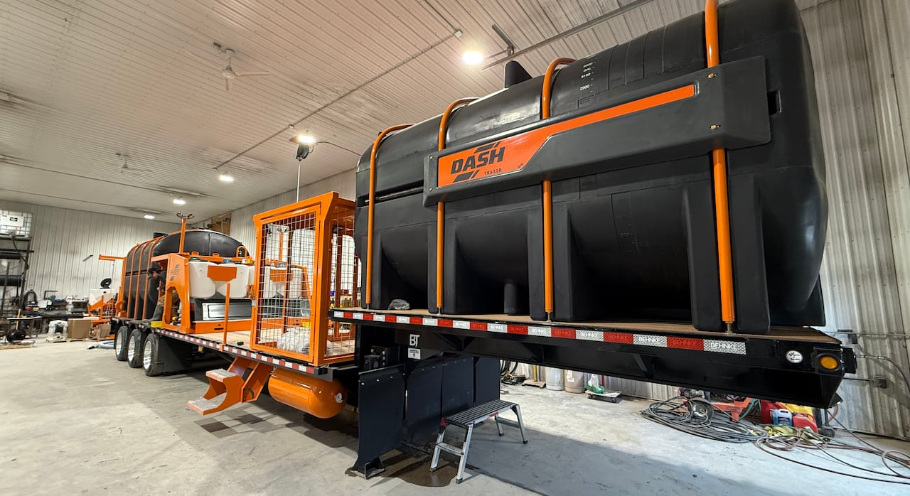 A large black plastic tank is attached to farm equipment.