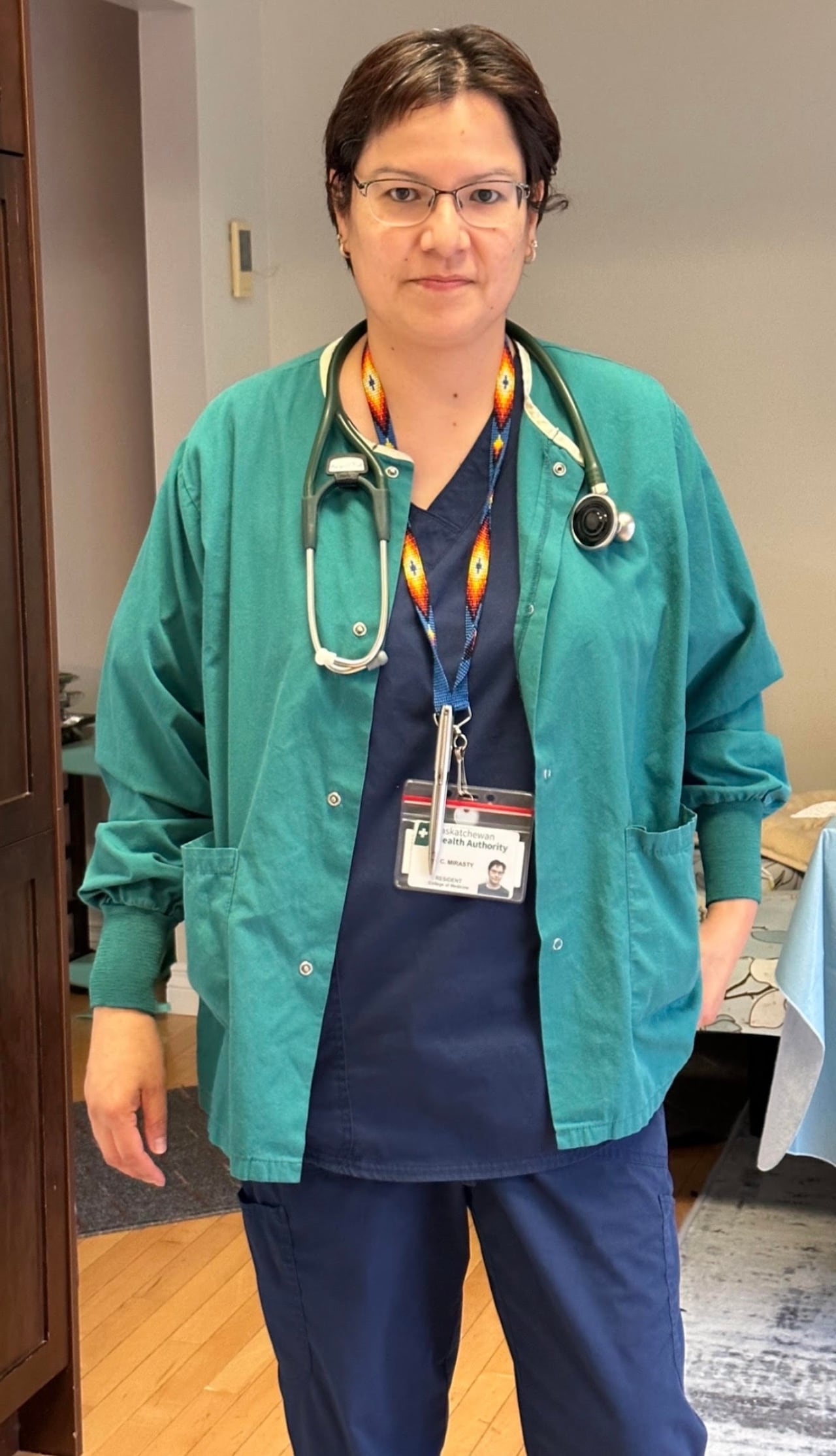 A woman doctor wearing scrubs with a stethoscope around her neck.