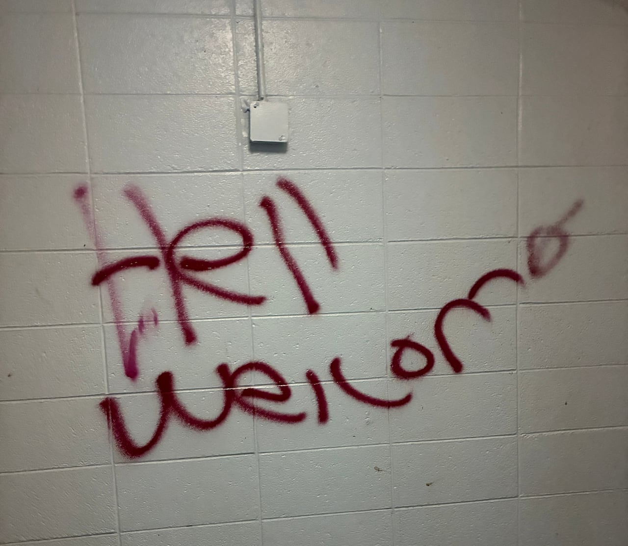 Red graffiti on a white stone wall.