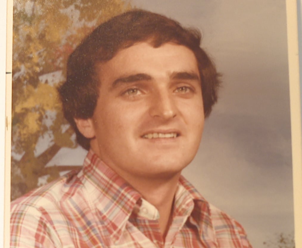 A man in a plaid shirt sits posed for a photo