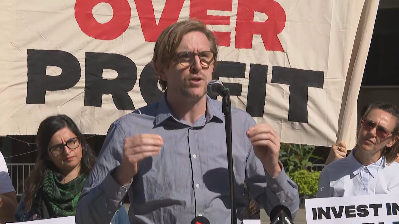 Man speaks at podium in front of city hall.