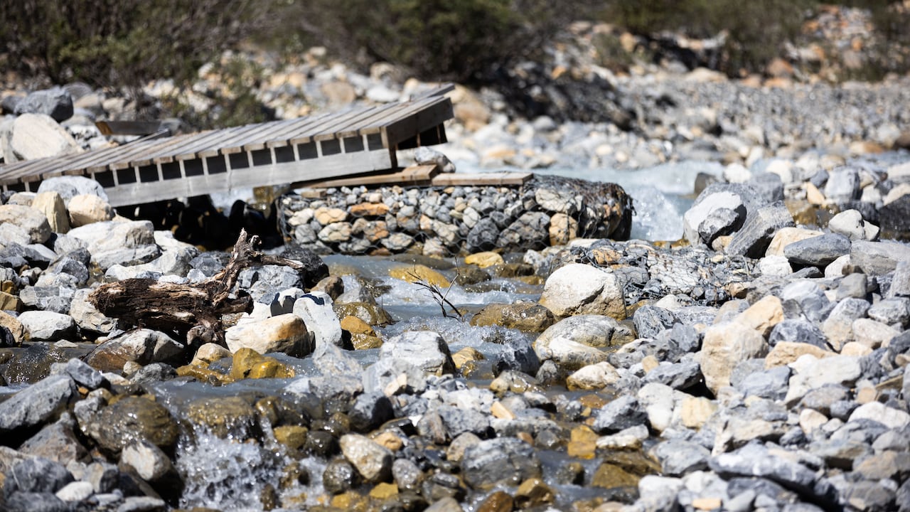 A broken bridge across a rocky river.