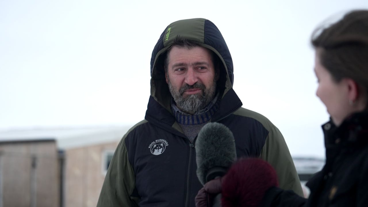 Man in jacket being interviewed with a mic