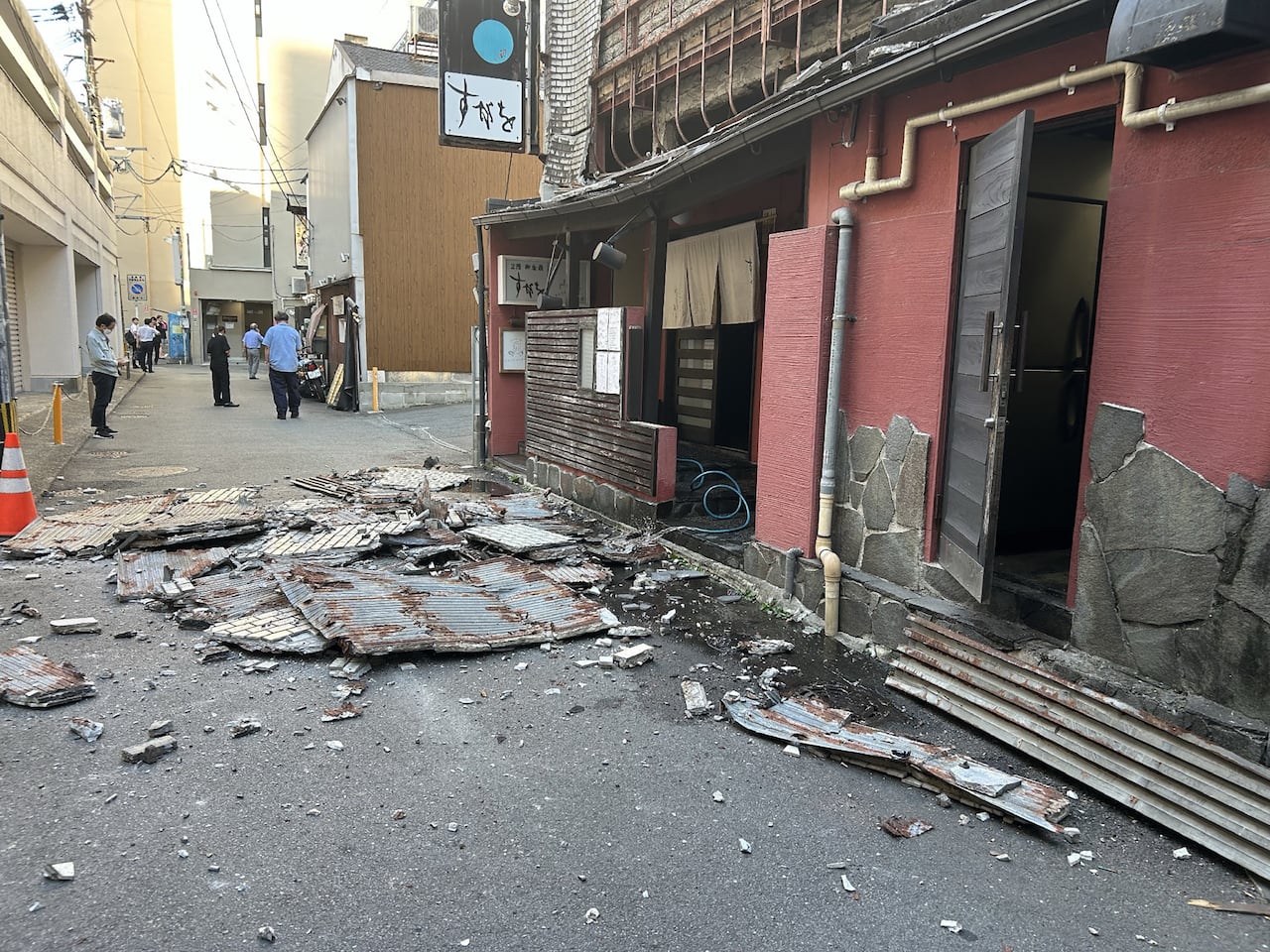 熊本市内一条狭窄街道，地面散落因地震倒塌的废墟