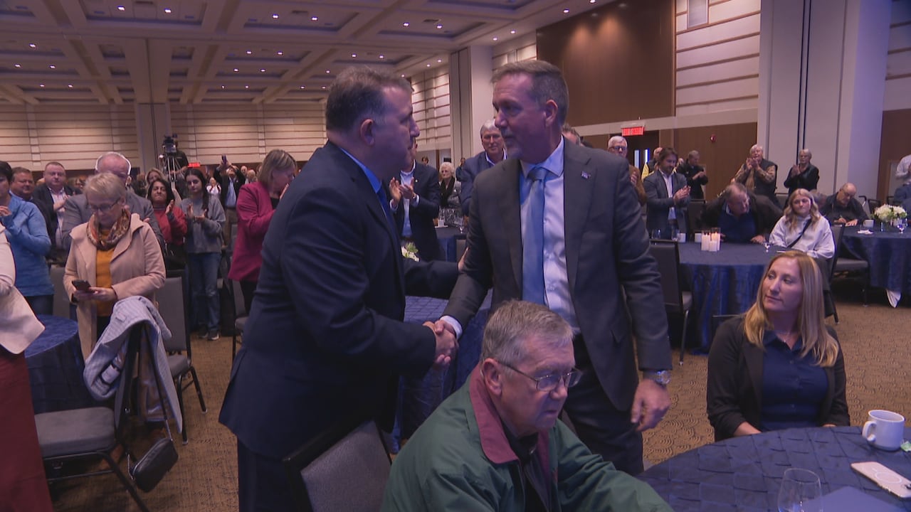 Two men shake hands at a convention.