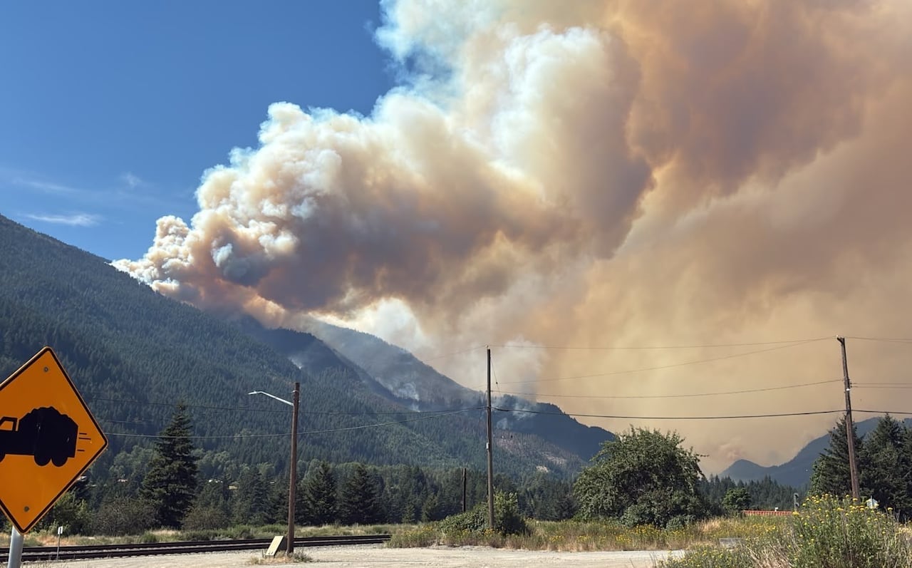 Wildfire smoke rises from mountains.