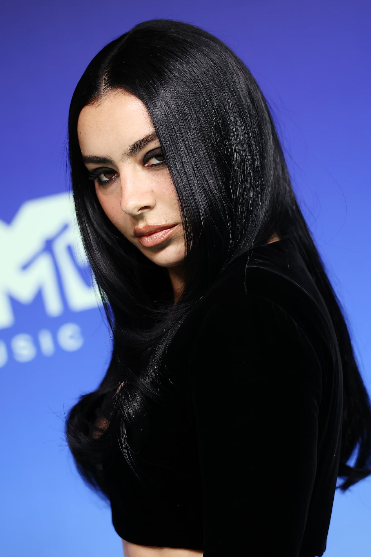 A woman with long jet-black hair poses.