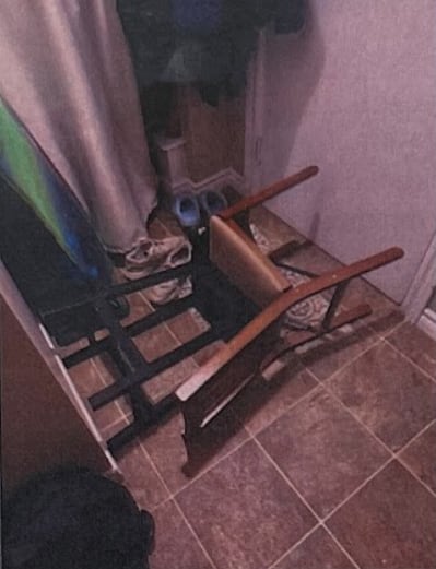 A high-back chair and stool on the floor in front of a door.