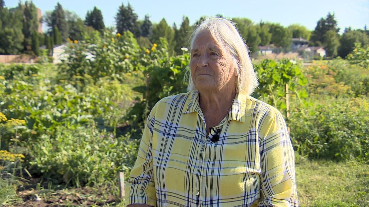 Woman in a yellow checkered shirt standing in a garden talking to a reporter