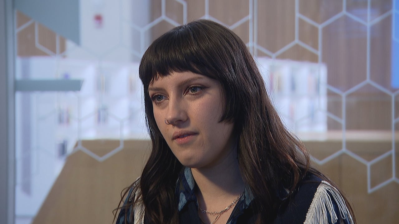 A woman with dark hair sits in an empty room.